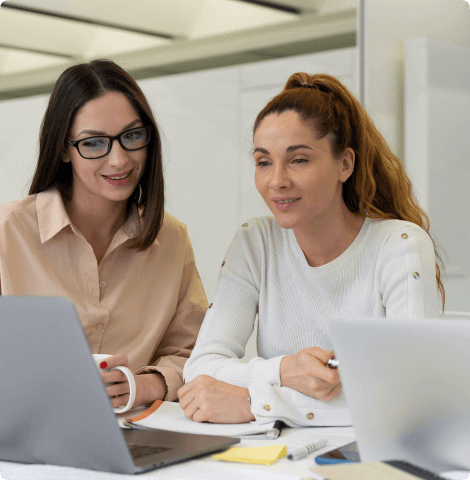 Two engineers working side by side at laptops